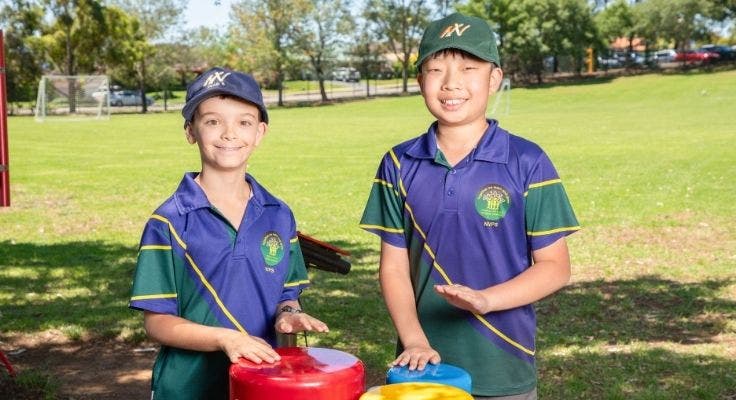 two students playing the playground drums on the field