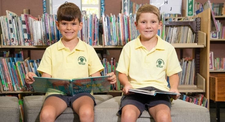 2 students with books in the library reading