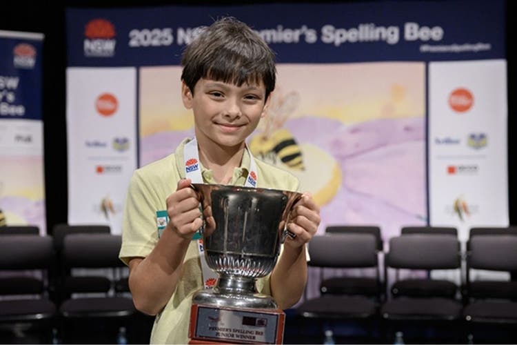 student showing his trophy for winning the Premier's Spelling Bee